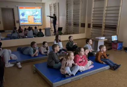 Dzieci leżą na materacach i na dużym ekranie oglądają prezentację o ptakach