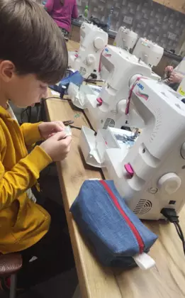 hłopczyk siedzi przy maszynie i sprawdza czy wszystkie części są w zestawie.