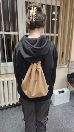 Uczestnik zajęć prezentuje na plecach swój beżowy workoplecak