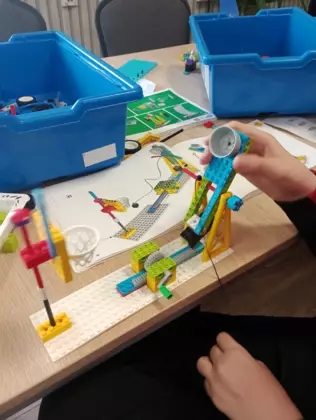 Uczestnik pokazuje zbudowane przez siebie z kolocków LEGO boisko do kosza.