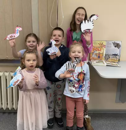 Wspólne zdjęcie po zajęciach. Dzieci trzymają w rękach zebry z papieru.