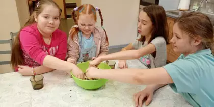 Dziewczynki w misce mieszają pokarm dla ptaszków.