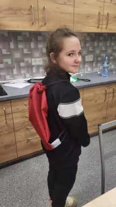 Uczestnik zajęć prezentuje na plecach swój czerwony workoplecak