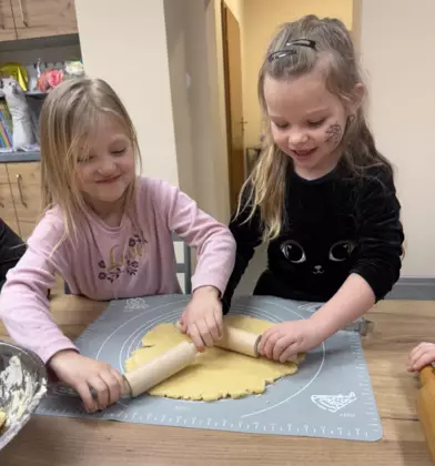 Dwie dziewczynki wałkują ciasto na ciasteczka.