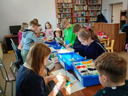 Dzieci budują pojazdy z kolcków LEGO.