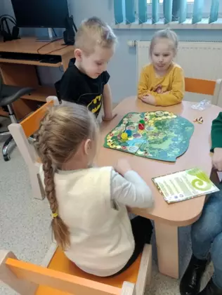 Dzieciaki w trakcie rozgrywki. Grają w grę planszową.