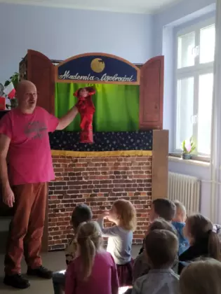 Pan tłumaczy dzieciom w jaki sposób używać pacynek.