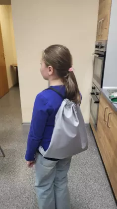 Uczestnik zajęć prezentuje na plecach swój szary workoplecak