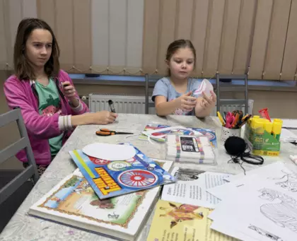 Dziewczynki malują paski na zebrze z papieru.