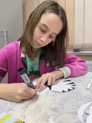 Dziewczynka maluje paski na zebrze z papieru.