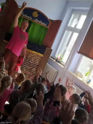 Pan tłumaczy dzieciom w jaki sposób używać pacynek.