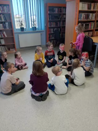 Dzieci siedzą w okręgu i grają w Lisek chodzi koło drogi.