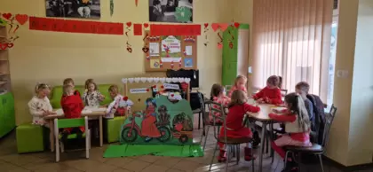 Grupa przedszkolaków w trakcie kolorowania walentynkowych obrazków.