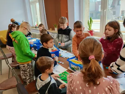 Dzieci budują pojazdy z kolcków LEGO.