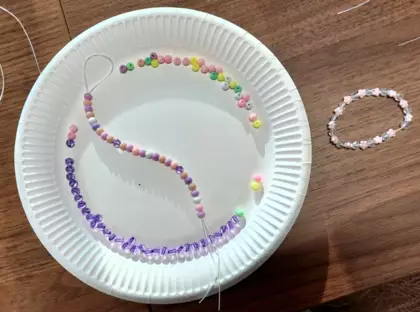 Koraliki nawleczone na nitkę  na talerzyku.