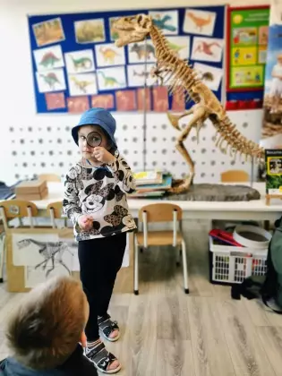 Dziewczynka jako paleontolożka patrzy przez szkło powiększające na skamieniałą kość