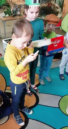 Chłopczyk patrzy przez szkło powiększające na skamieniałą kość