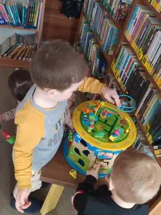 Dzieci w bibliotece bawią się zabawką edukacyjną.