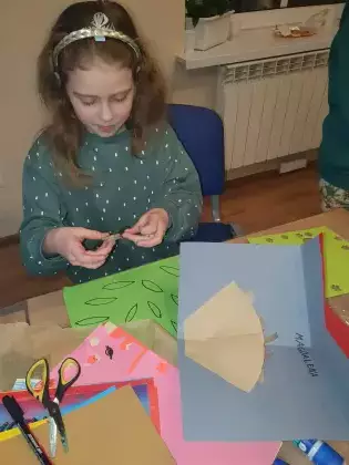 Dziewczynka wycina z kolorowego papieru gniazdo jaskółek