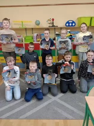 Dzieci na zdjęciu grupowym z pracami plastycznymi w rękach.