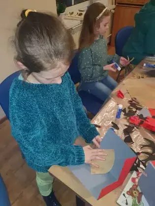 Dziewczynka w bibliotece tworzy pracę plastyczną