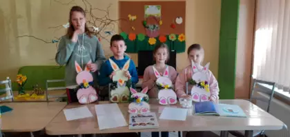 Dzieci pozują do wspólnego zdjęcia ze swoimi pracami stojąc przy stole.