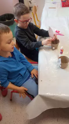 Chłopczyk napełnia swoją doniczkę ziemią