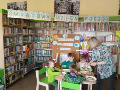 Pani z biblioteki pomaga dzieciom w pracy plastycznej