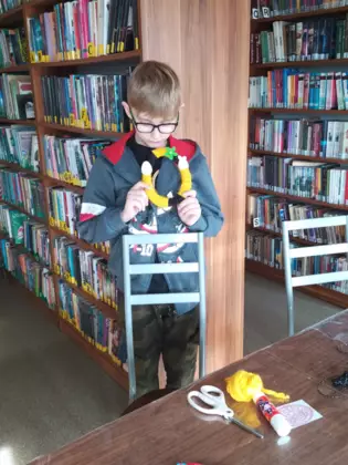 Chłopak prezentyje wielkanocne jajko oplecione włóczką.