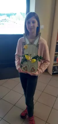 Dziewczynka trzyma w rękach królika wielkanocnego zrobionego z tektury.