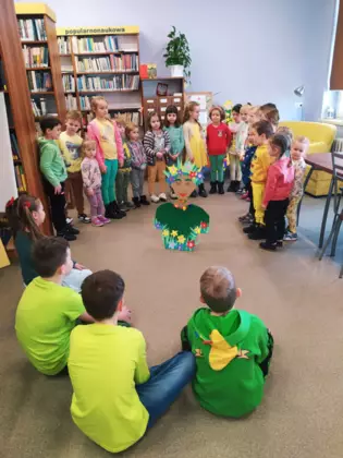 Dzieci siedzą wokół Pani Wiosny i czytają wiersze.
