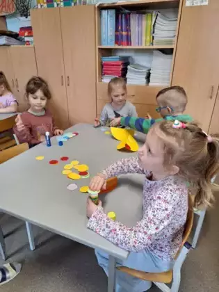 Dzieci wycinają kółka z kolorowego papieru.