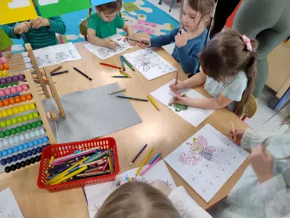 Przedszkolaki kolorują wiosenne obrazki.