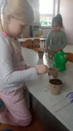 Dziewczynka sadzi ziarenka w ziemi