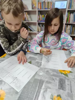 Chłopiec i dziewczynka rozwiązują zagadki związane z dinozaurami.