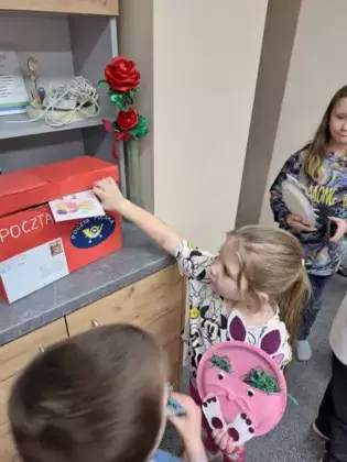 Uczestnicy zajęć wrzucają listy do papierowej skrzynki pocztowej.