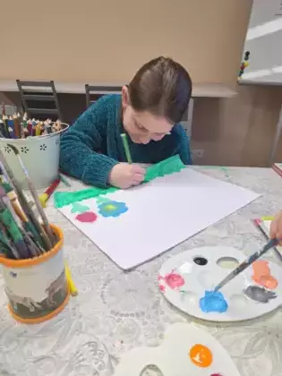 Dziewczynka maluje farbami wiosenną łąkę.