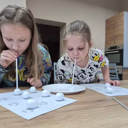 Dziewczyny zbierają słomką jajeczka wielkanocne.