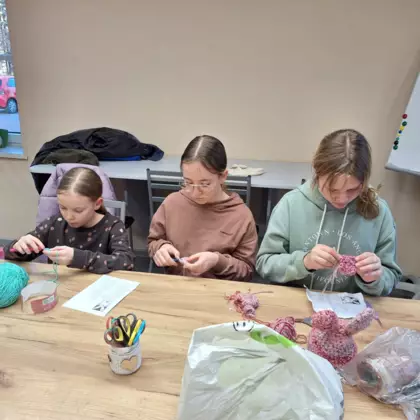 Trzy dziewczyny siedzą koło siebie i szydełkują wielkanocnego królika.