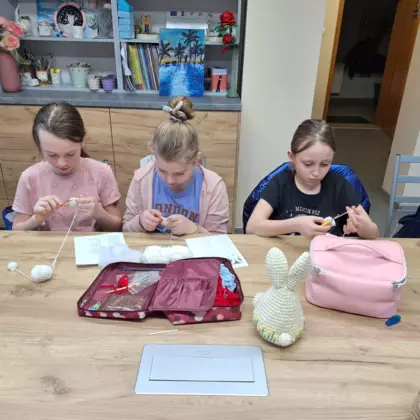 Trzy dziewczyny szydełkują ozdoby wielkanocne.