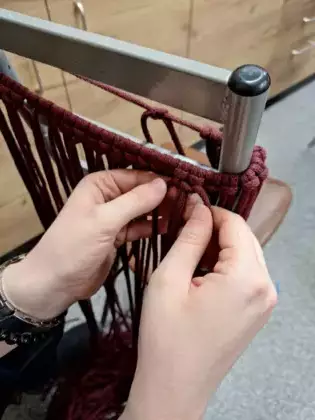 Uczestniczka zajęć tworzy makramową torebkę.