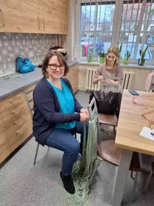 Uczestniczka zajęć wyplata sznurki makramowe.