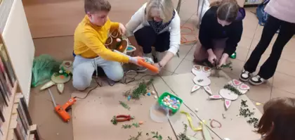 Dzieci bukszpanem oklejają królika wielkanocnego.