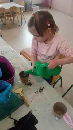 Dziewczynka podlewa konewką posadzone ziarenka