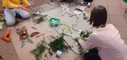 Dzieci bukszpanem oklejają królika wielkanocnego.