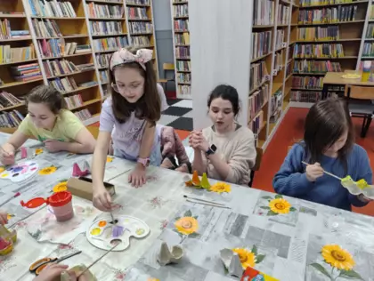 Dzieci farbami malują papierowe kurki.