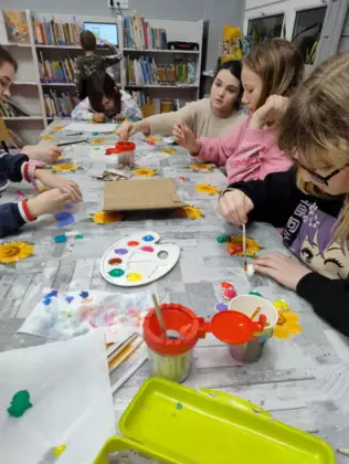 Dziewczynki malują farbkami magnesowe dinusie.