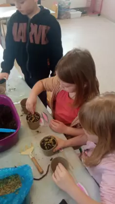 Dwie dziewczynki i chłopczyk sadzą ziarenka