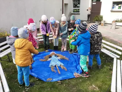 Przedszkolaki leją Marzannę wodą.