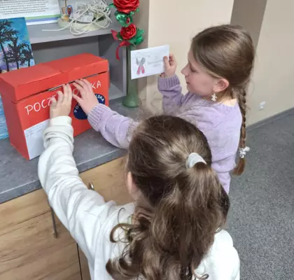 Uczestnicy zajęć wrzucają listy do papierowej skrzynki pocztowej.